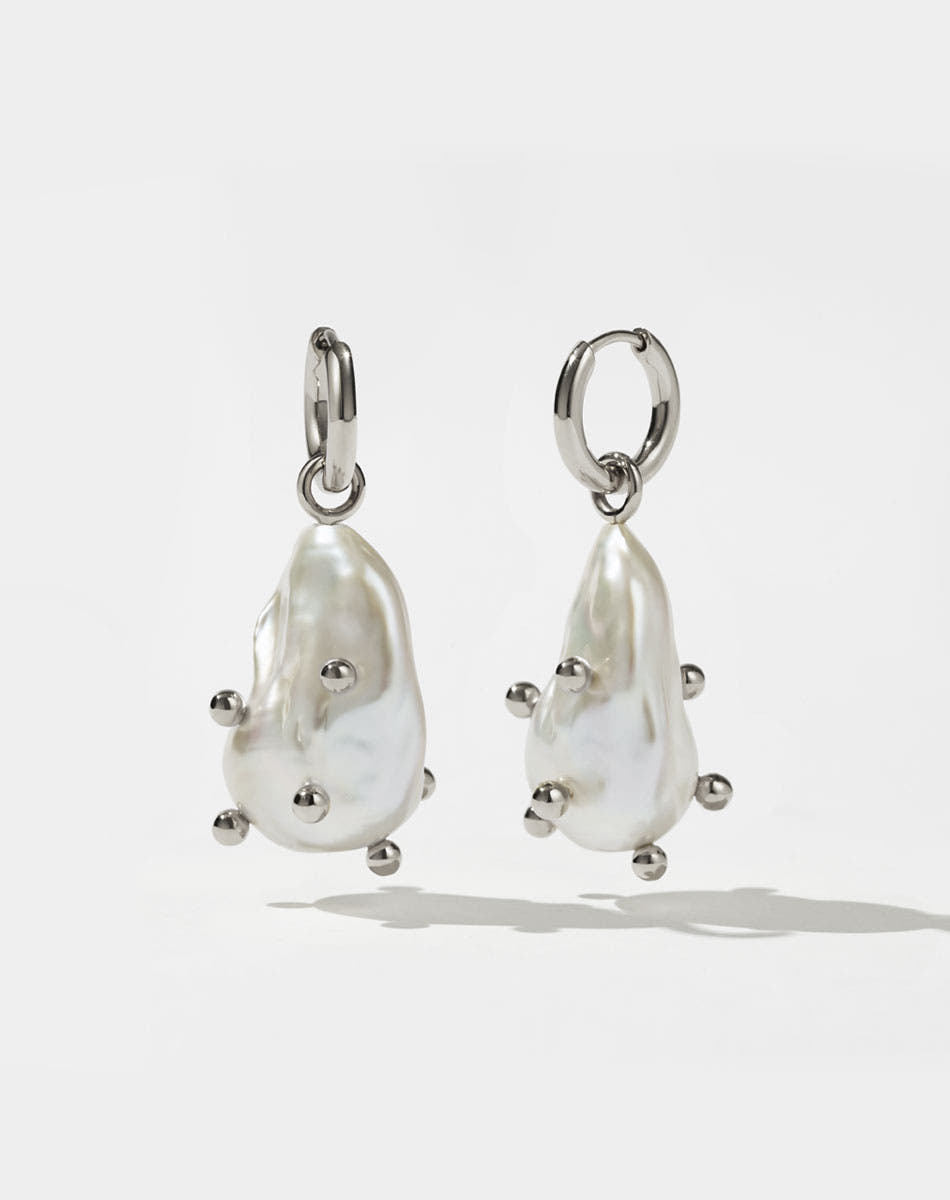 A pair of sterling silver drop earrings featuring baroque pearls with barnacles.