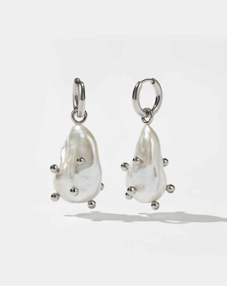 A pair of sterling silver drop earrings featuring baroque pearls with barnacles.