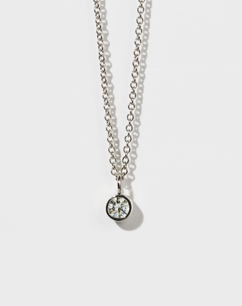 A sterling silver necklace with a round brilliant stone in a bezel setting on a fine chain.