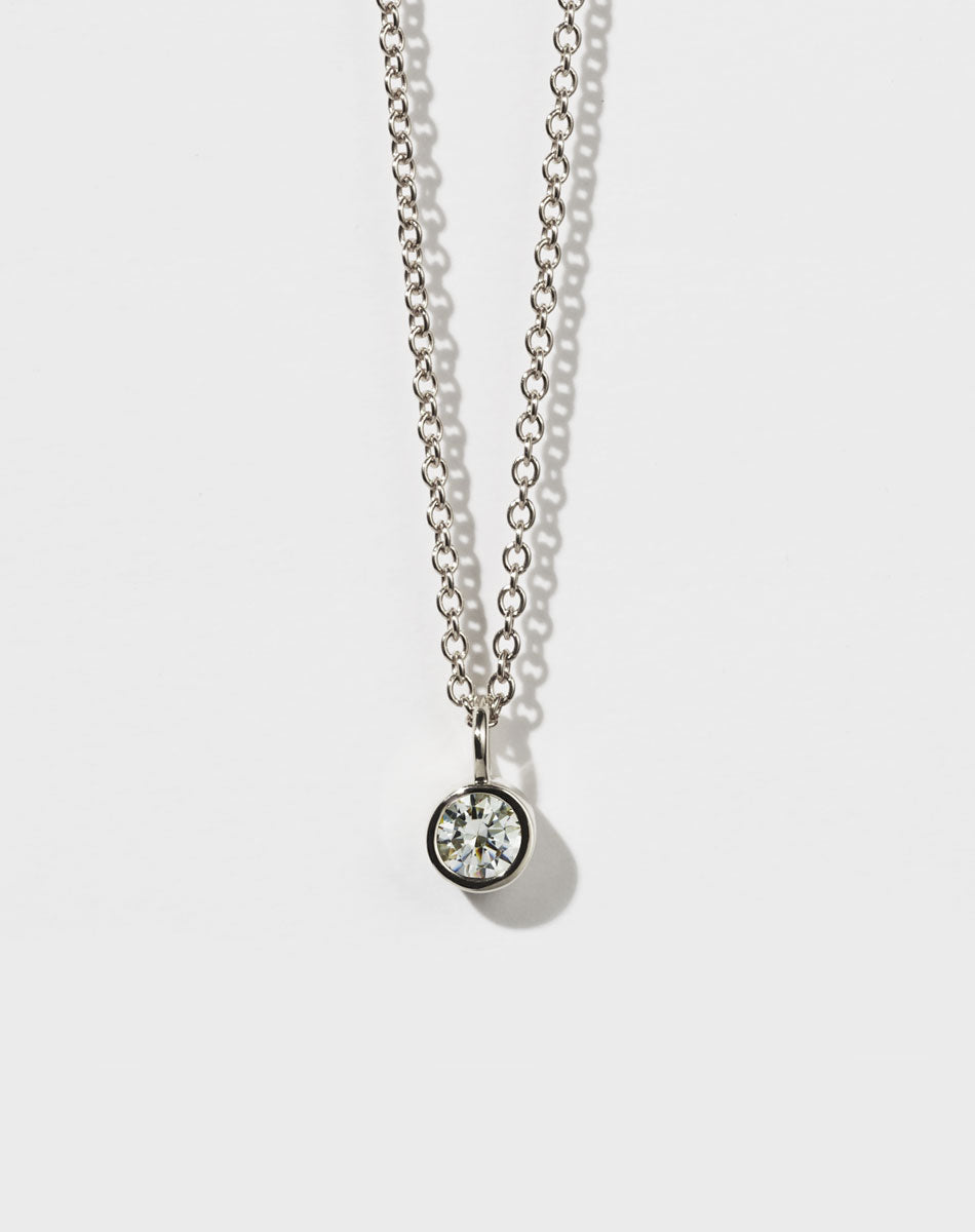 A sterling silver necklace with a round brilliant stone in a bezel setting on a fine chain.