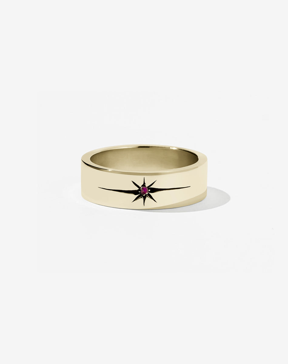 A 9ct yellow gold flat band with a central ruby set in an elongated star setting, creating a dramatic effect.