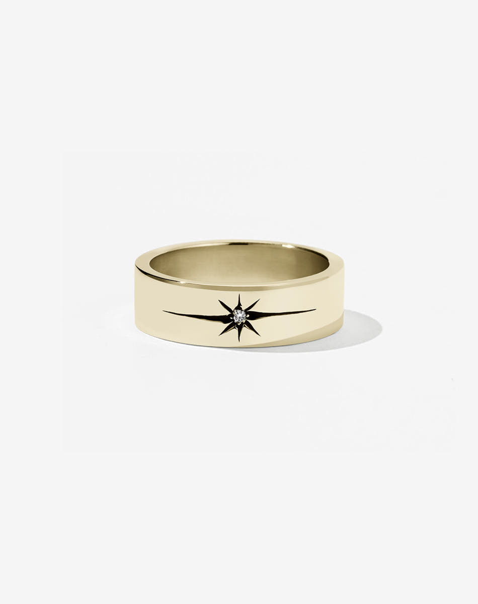 A 9ct yellow gold flat band with a central diamond set in an elongated star setting, creating a dramatic effect.