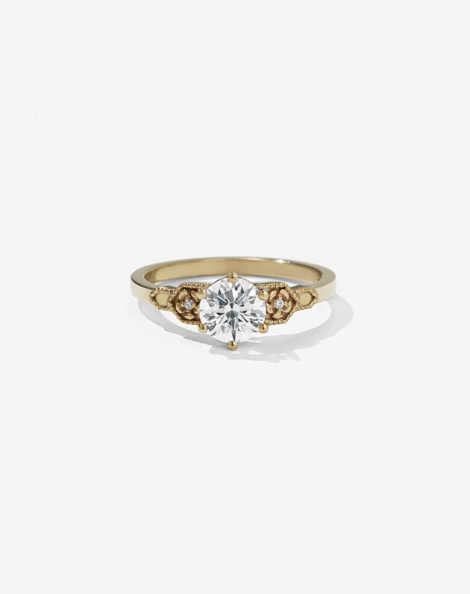Meadowlark Jewellery’s vintage inspired 0.8ct Eternal Solitaire Engagement Ring in 9ct Yellow Gold, claw set with a round brilliant cut white diamond centre stone.  Atop a fine square band. A timeless, floral Ceremonial design made to order in New Zealand. Pair with the diamond pave set Eternal Wedding Band.