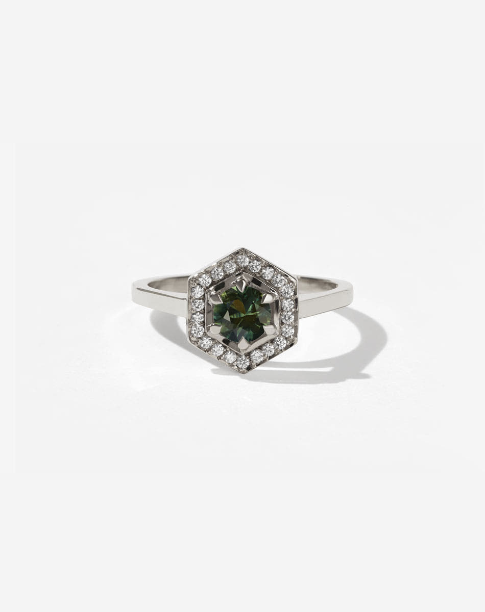 Meadowlark Jewellery’s iconic Hex Engagement Ring 0.5ct in 9ct White Gold, claw set with 0.61ct round brilliant cut green sapphire centre stone, surrounded by a hexagon halo of pave set white diamonds. Fully traceable and ethically sourced blue and green sapphires from Queensland, Australia. One of our most beloved and modern Ceremonial designs, made to order in New Zealand. Pair with our bestseller, the Diamond Eternity Band.
