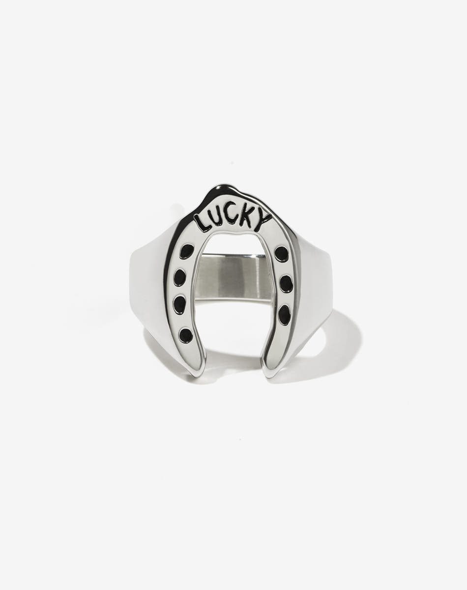 A sterling silver ring with a wide band that flares out into a shape resembling a lucky horseshoe, with the word 'LUCKY' inscribed