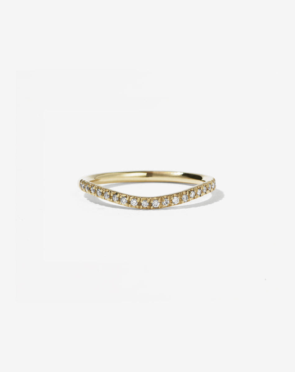 A fine round yellow gold band with a gentle curve, featuring small white diamonds set in a French pave style halfway around the band.
