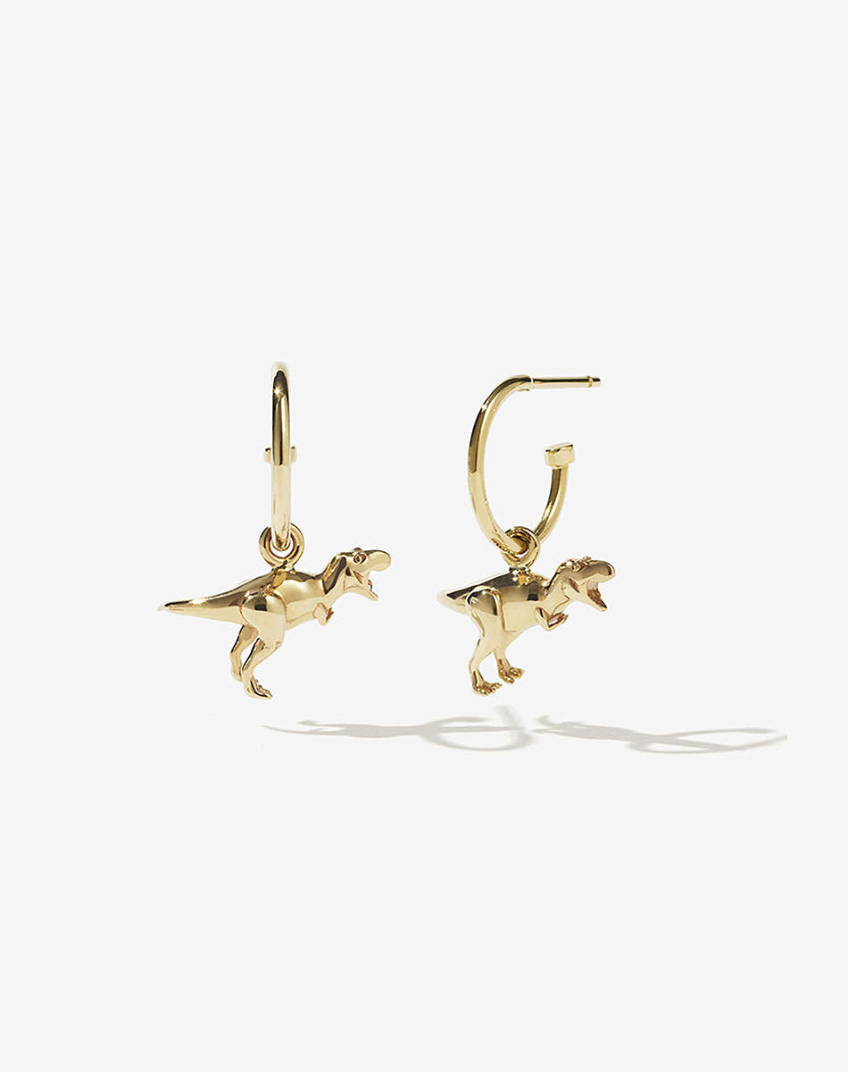 A pair of gold-colored dinosaur charms attached to small gold hoop earrings.