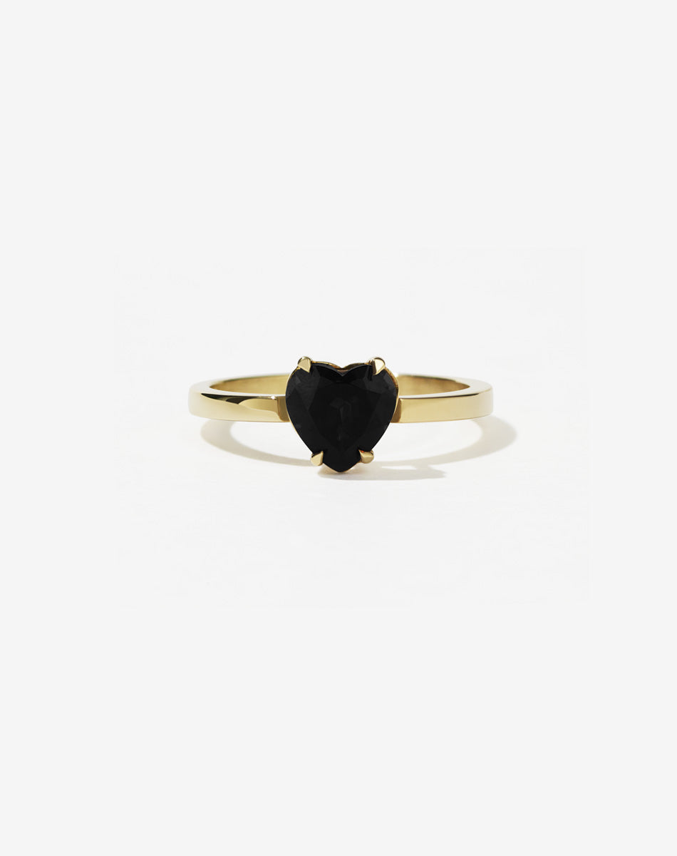 A gold ring with a heart-shaped cut onyx stone set in a simple claw setting on a delicate band.