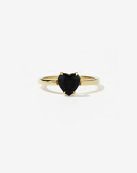 A gold ring with a heart-shaped cut onyx stone set in a simple claw setting on a delicate band.