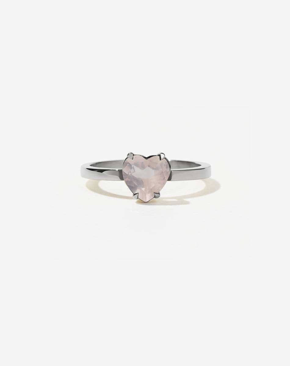 A silver ring with a heart-shaped cut rose quartz stone set in a simple claw setting on a delicate band.