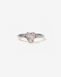 A silver ring with a heart-shaped cut rose quartz stone set in a simple claw setting on a delicate band.