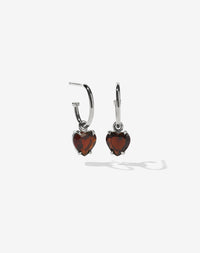 A pair of sterling silver hoop earrings with heart-shaped Thai garnet stones set in a claw setting.