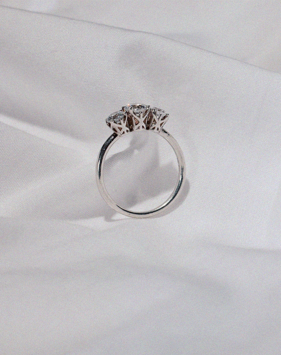 A classic three stone engagement ring in white gold with diamonds and intricately designed settings.