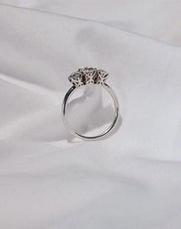 A classic three stone engagement ring in white gold with diamonds and intricately designed settings.