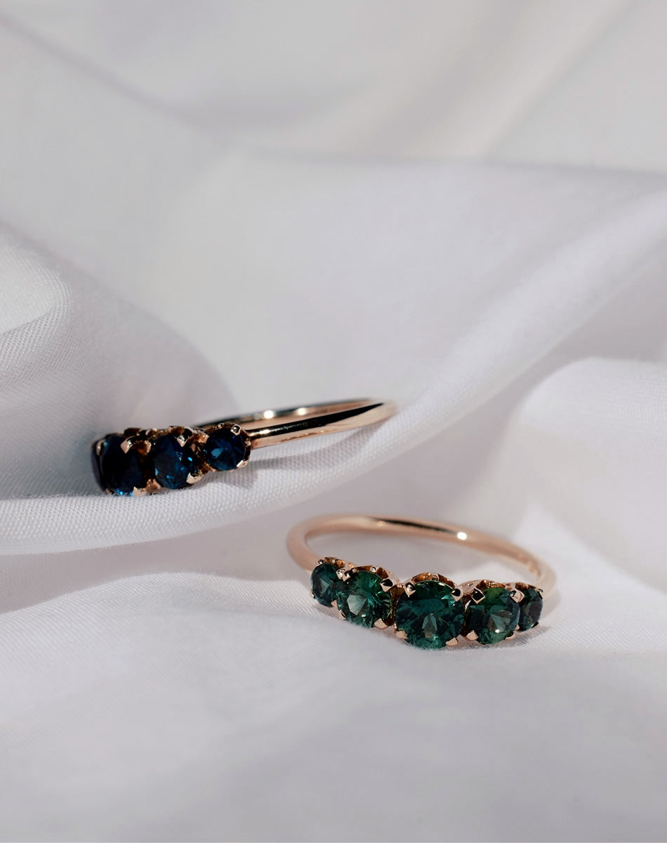 Yellow gold engagement rings set with green and blue sapphires.