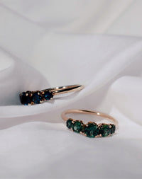 Yellow gold engagement rings set with green and blue sapphires.