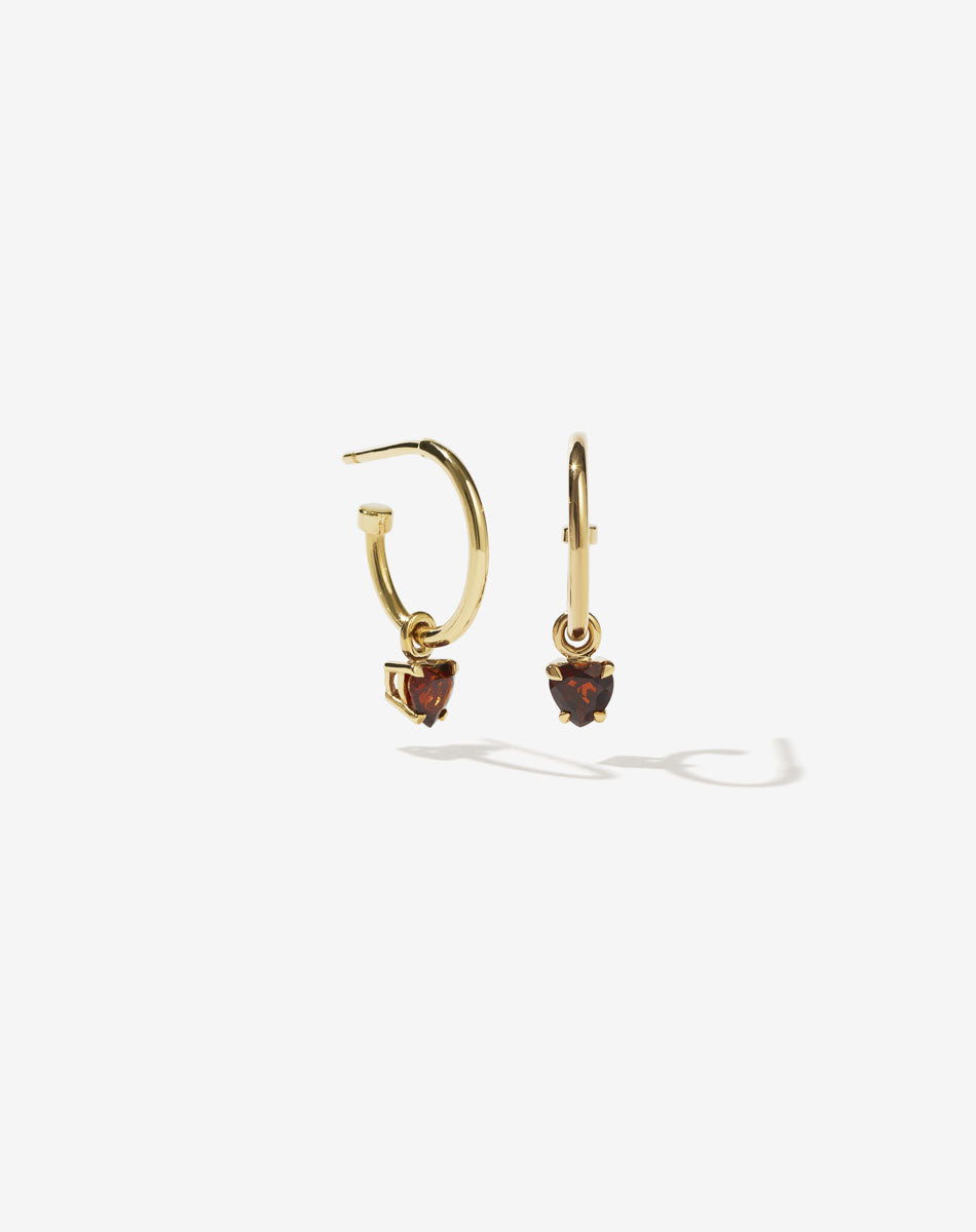 A pair gold plated hoop earrings with heart-shaped garnet stones set in claw settings.