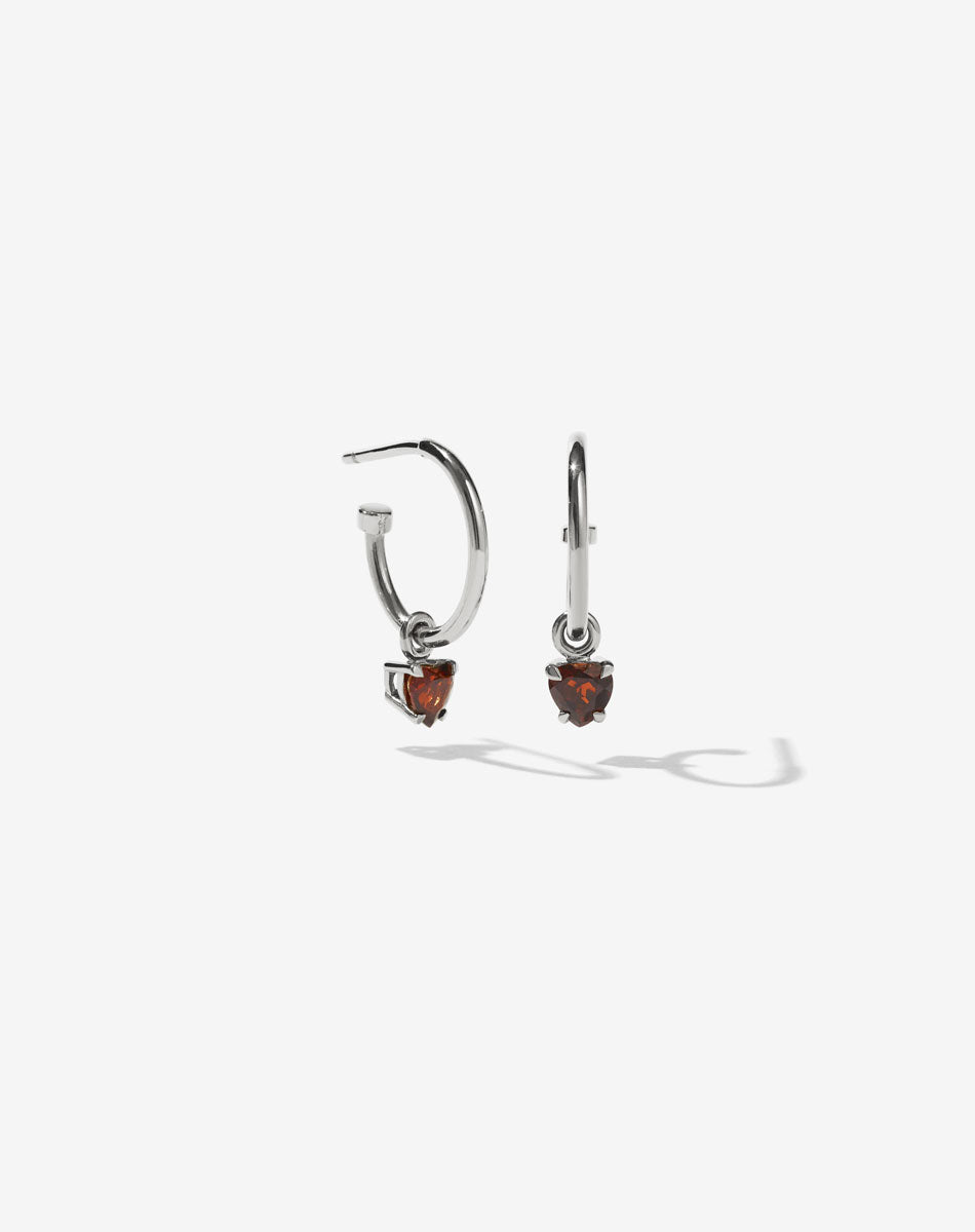 A pair of sterling silver hoop earrings with heart-shaped Thai garnet stones set in claw settings.