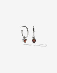 A pair of sterling silver hoop earrings with heart-shaped Thai garnet stones set in claw settings.