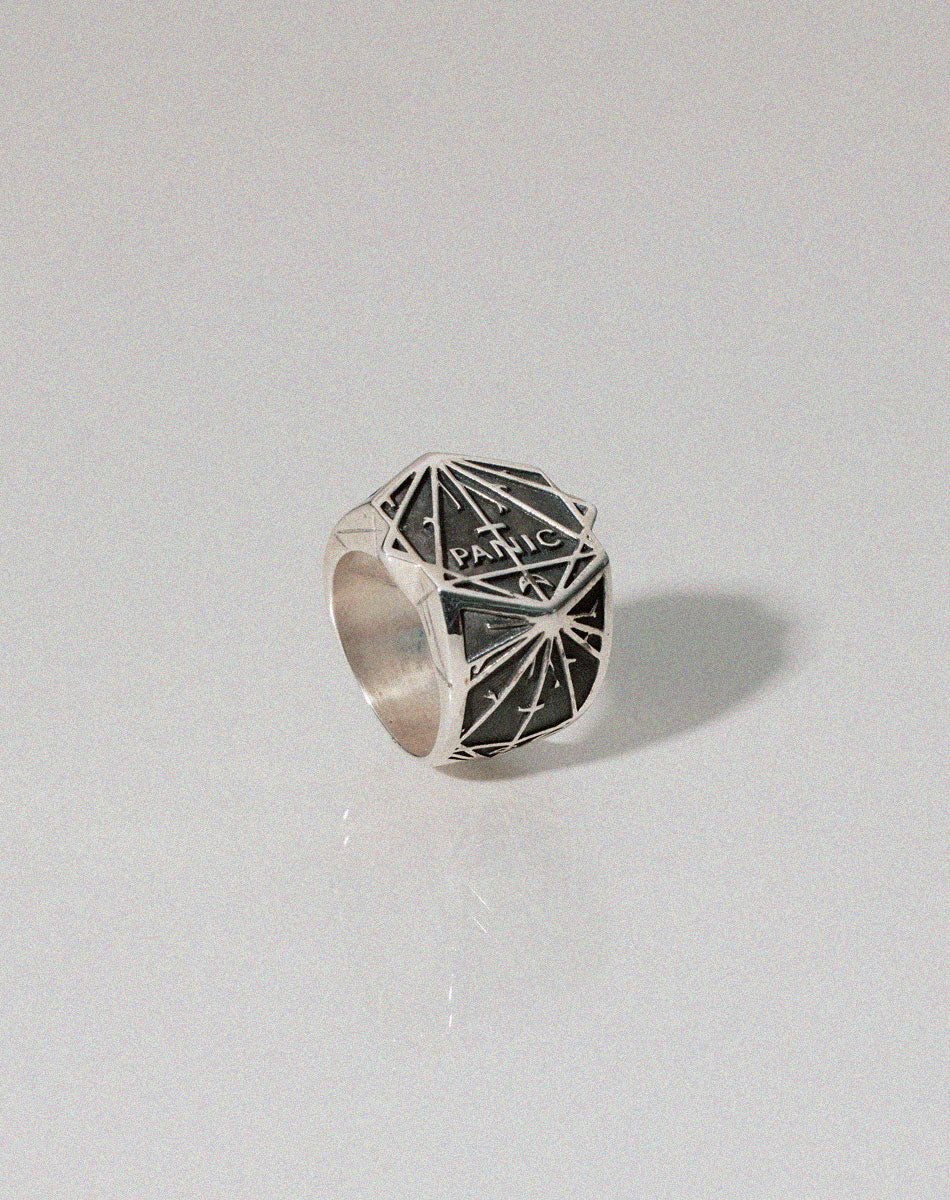 A heavy weighted sterling silver ring with geometric artwork and the word Panic. Designed in collaboration with NZ artist Andrew McLeod.