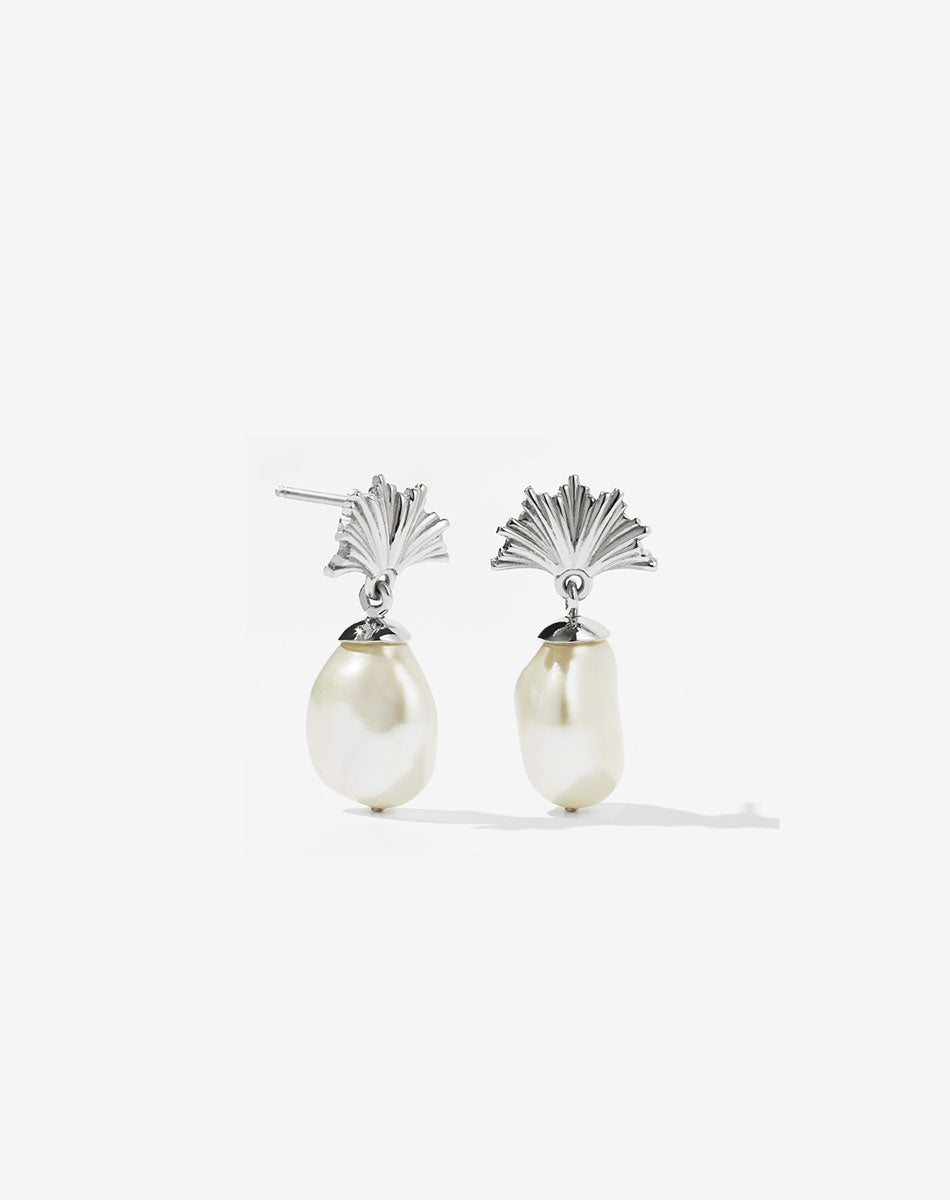A pair of sterling silver drop earrings featuring a fan-shaped ginko leaf design atop a large freshwater pearl.